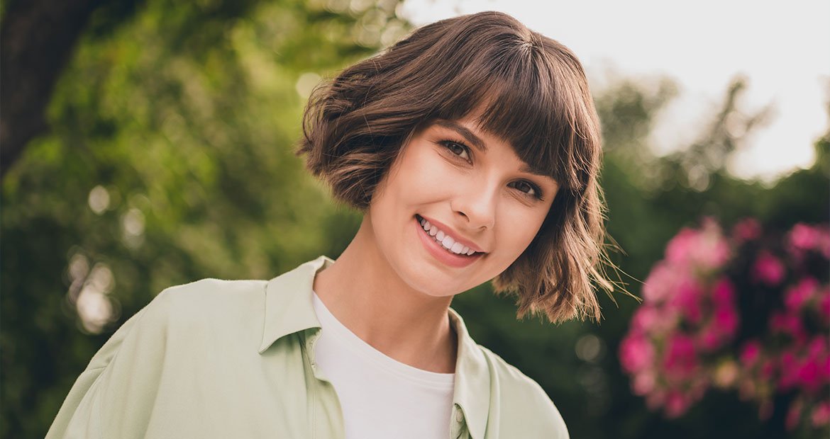 Mulher jovem com o corte de cabelo curto ondulado chamado de french bob